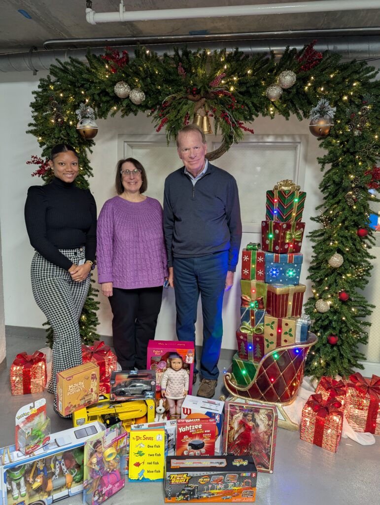 Three Brownson team members standing by their donation for Toys for Tots